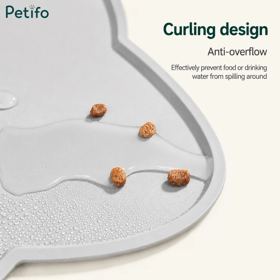 Close-up of a gray silicone pet mat demonstrating its anti-overflow curling design holding spilled kibble and water.