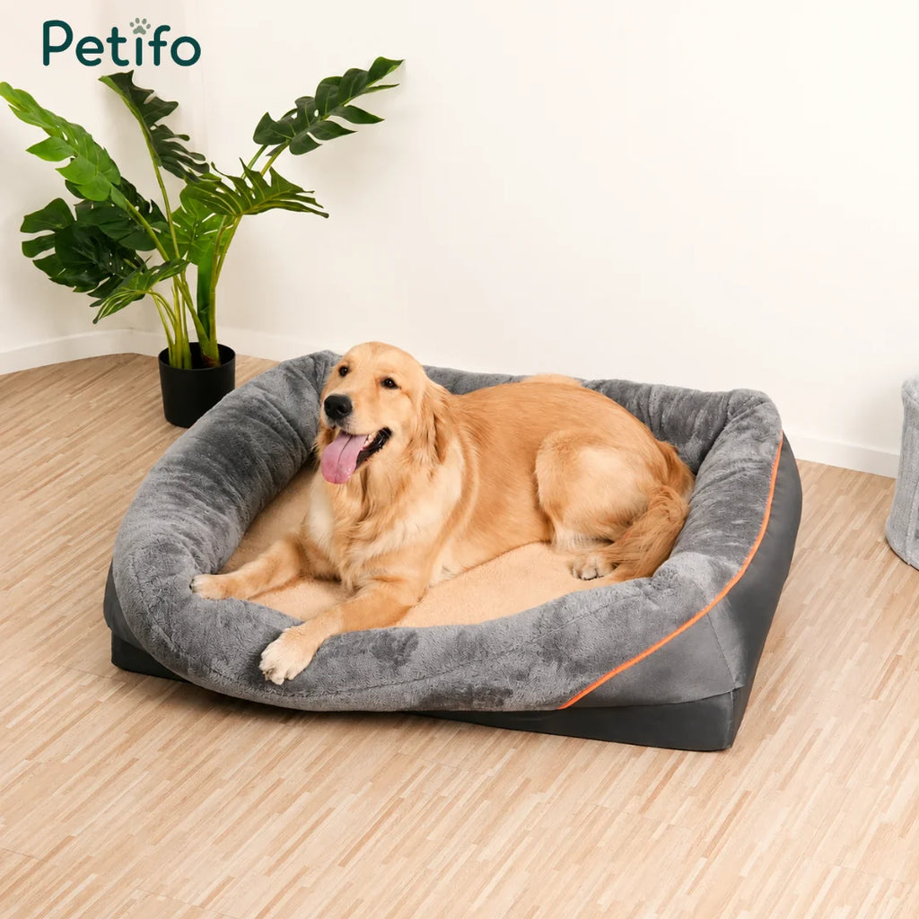 A happy golden retriever resting comfortably in a spacious, grey, and soft-bolstered Petifo orthopedic pet bed.