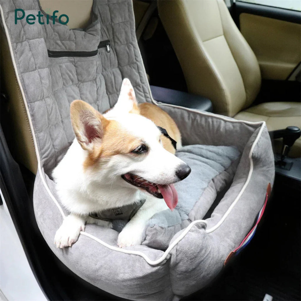 A happy corgi relaxing in a soft, grey Petifo pet car seat securely installed in the front passenger seat of a vehicle.